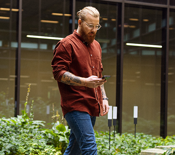 En mand går igennem en have med sin telefon i hånden