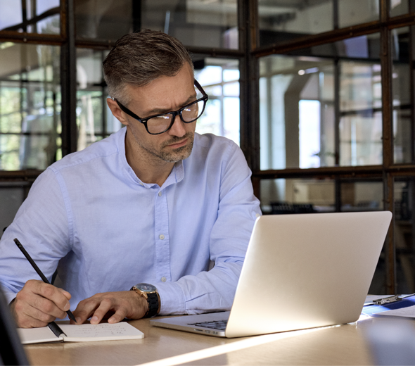 Mads ser på computer og skriver på blok