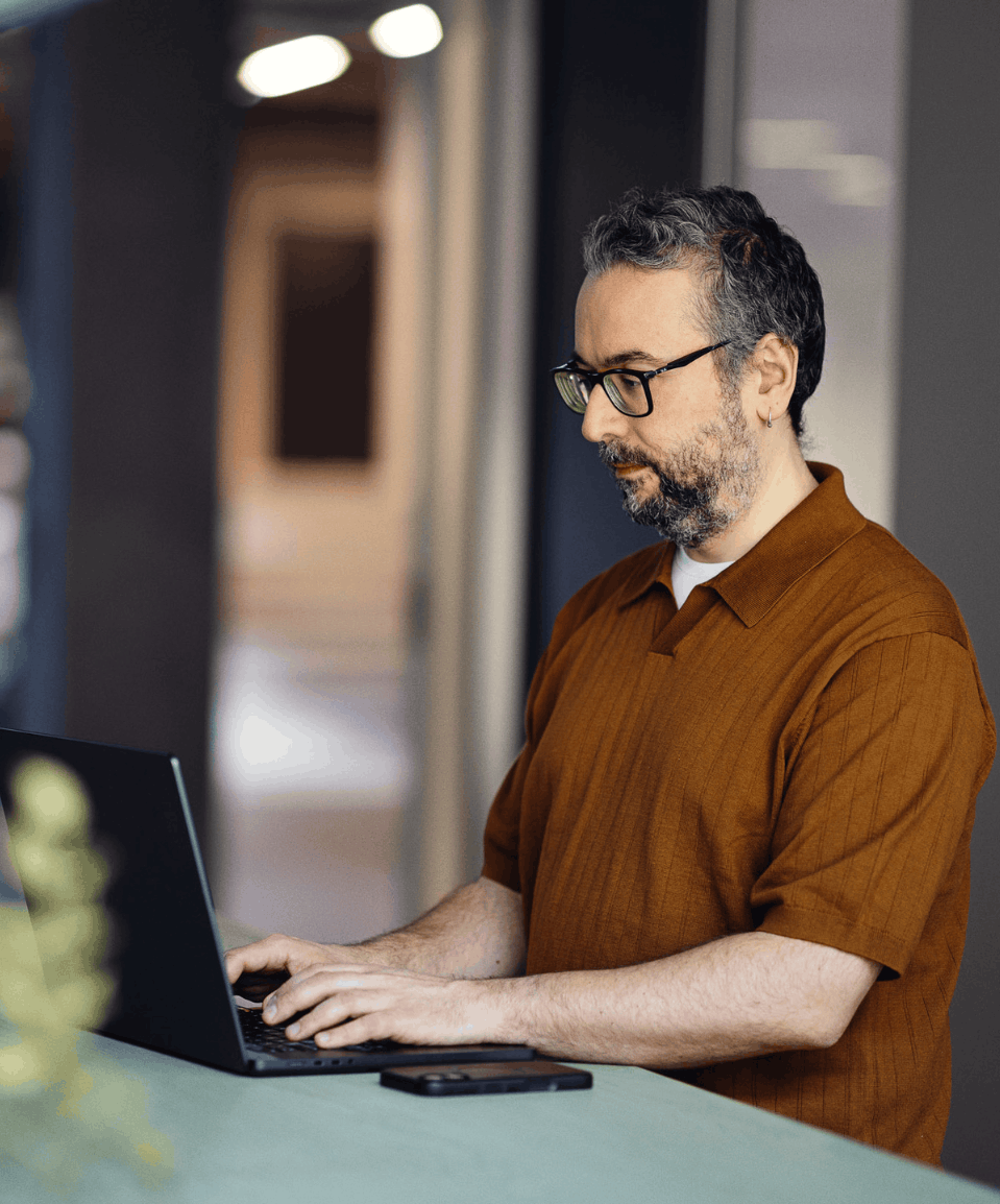 Et billede af en mand, der står og kigger ned på en computer