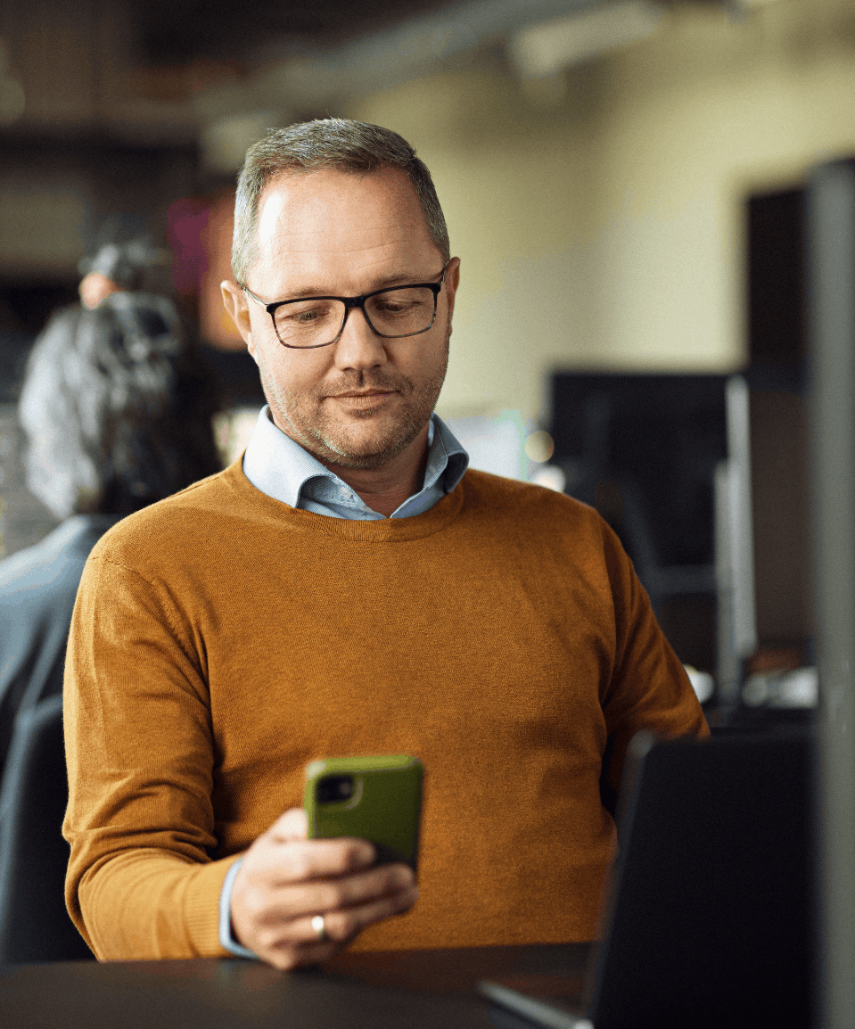 Et billede af en mand, der sidder og kigger på en telefon