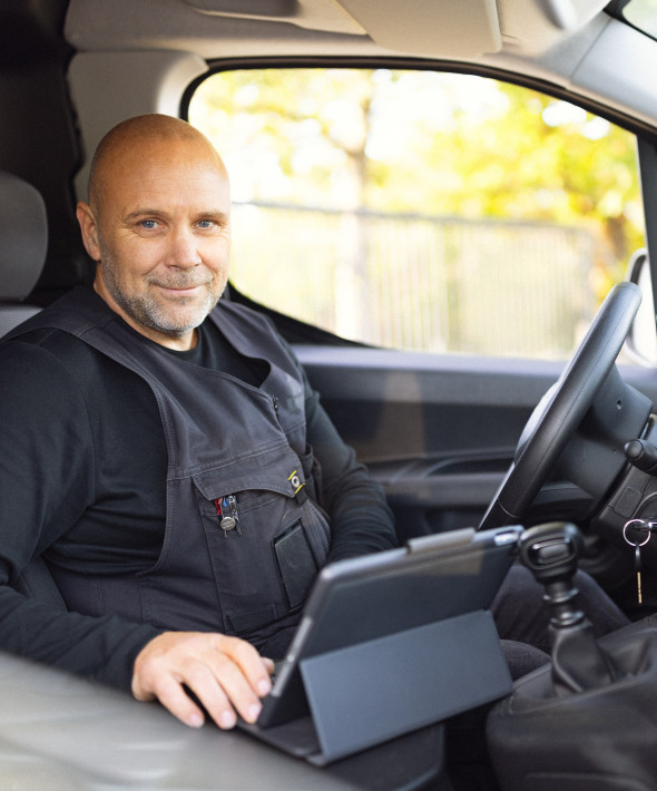 En mand sidder i en varevogn med en tablet
