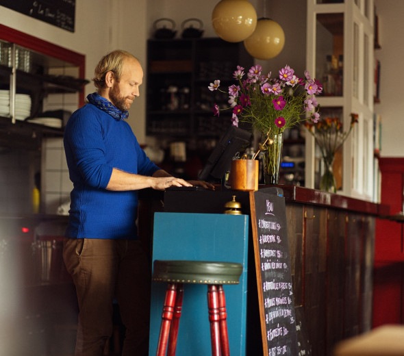 En mand står og kigger på en computer i en restaurant