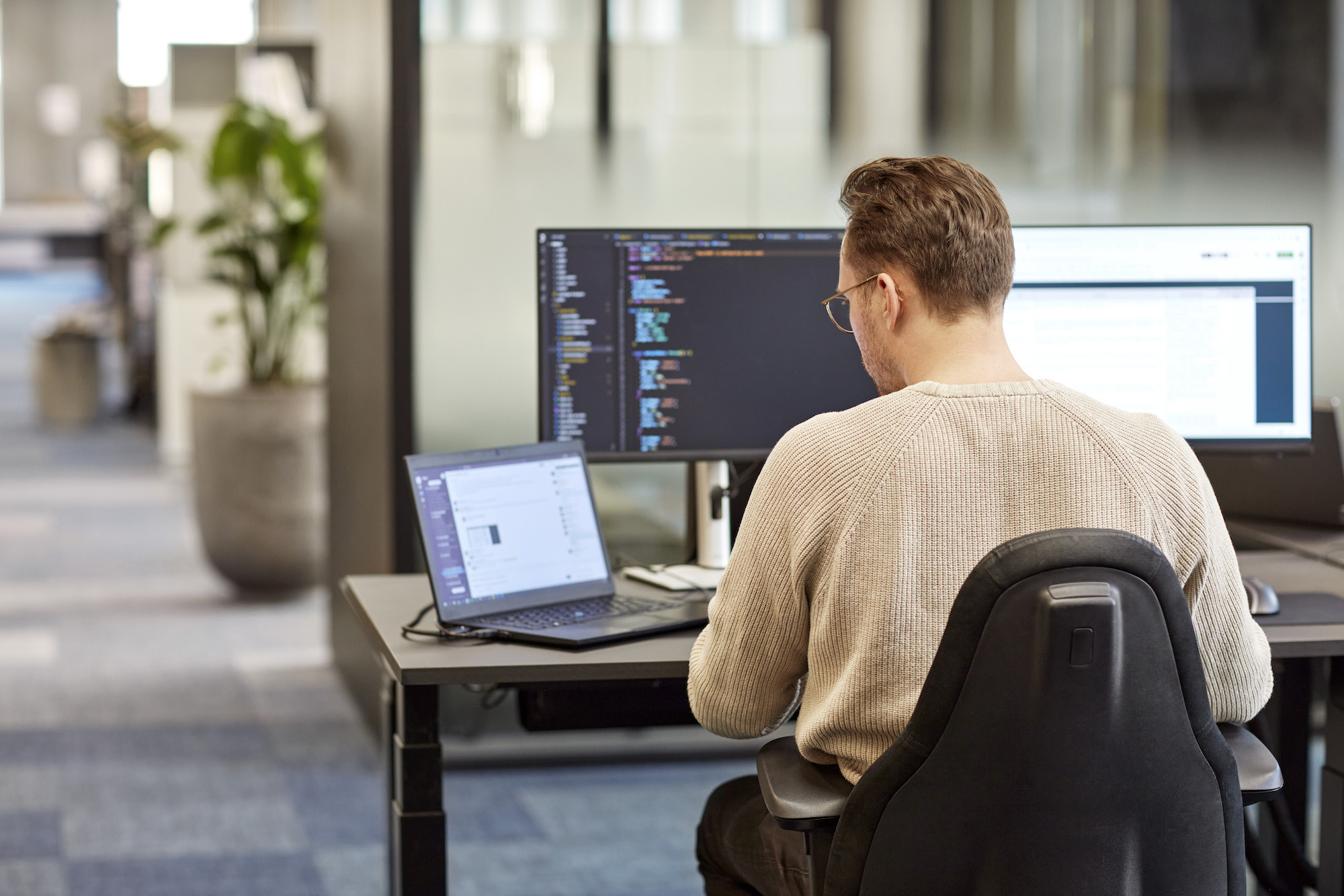 En mand sidder og arbejder med kode på en arbejdsplads