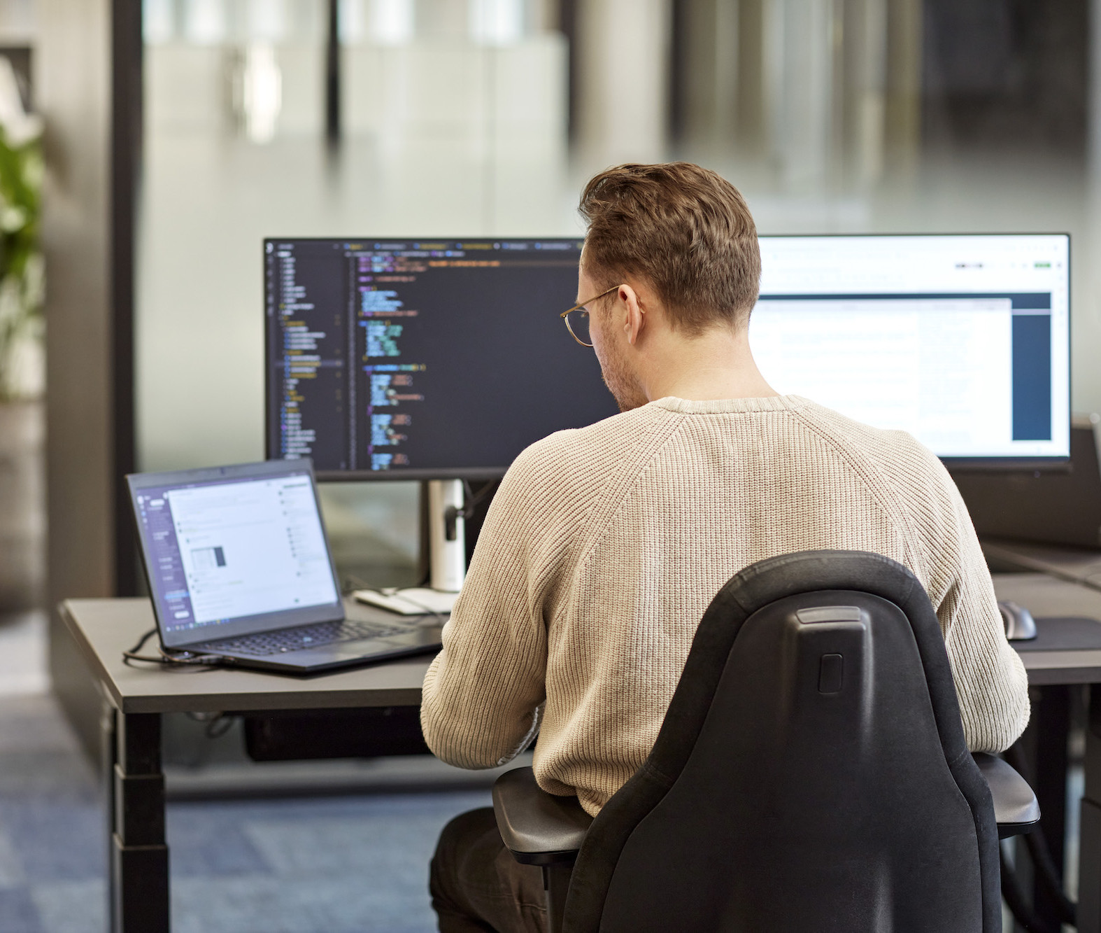En mand sidder og arbejder med kode på en arbejdsplads