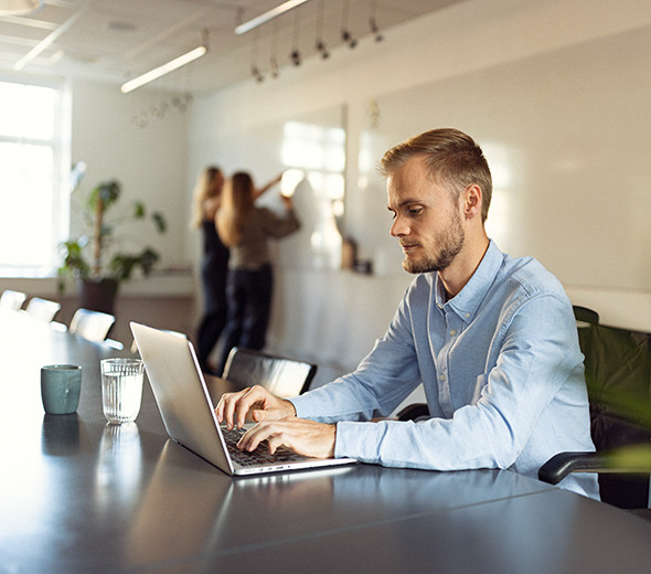 En mand sidder og skriver på en computer på en arbejdsplads