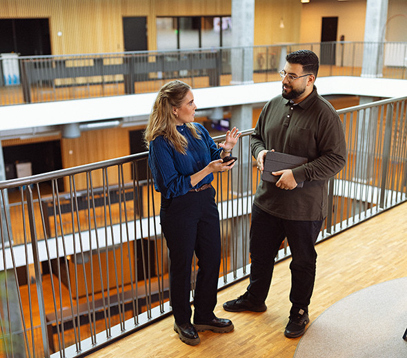 To mennesker står og taler sammen på en arbejdsplads