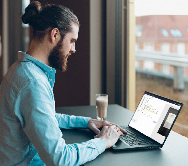 Mand sidder og skriver på sin bærbar med workflows i e-conomic åbent