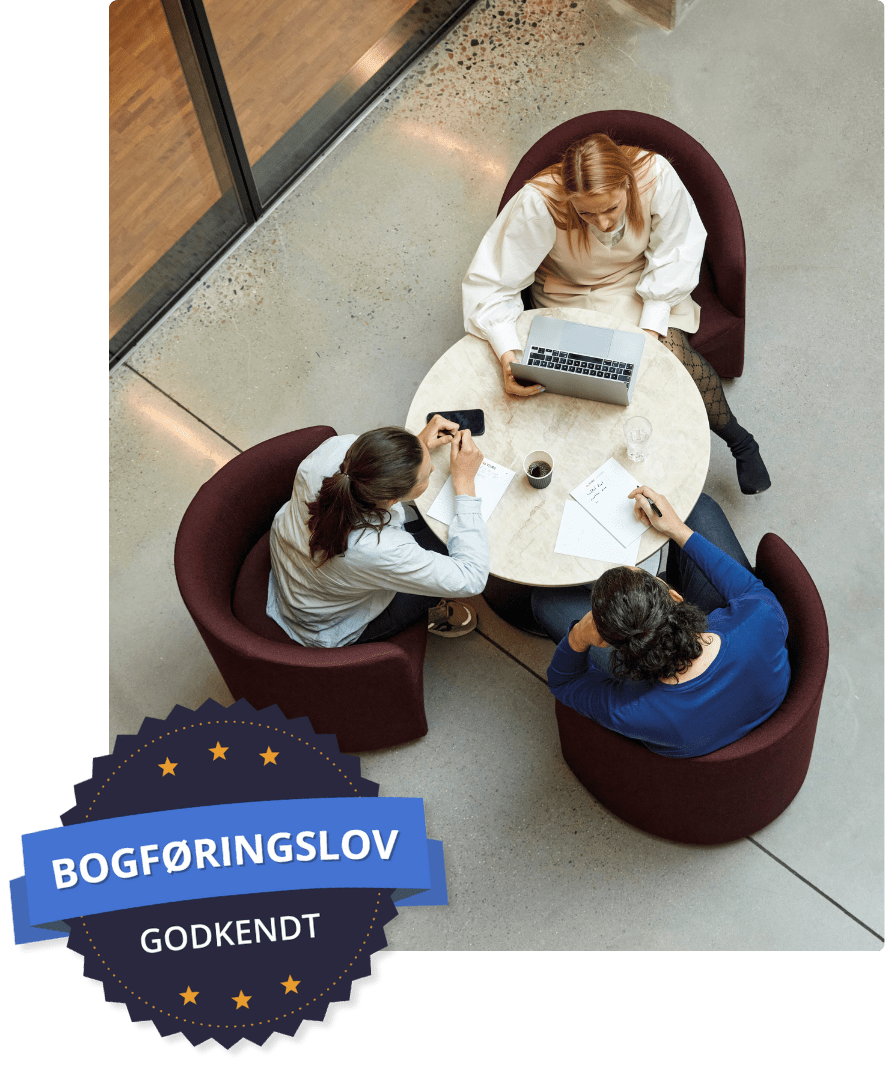 Tre personer sidder ved et rundt bord og snakker sammen, hvor billedet er taget oppefra
