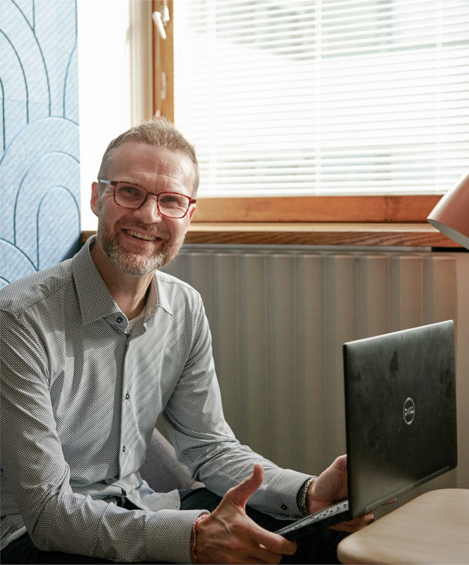 mand sidder og smiler med bærbar på skødet