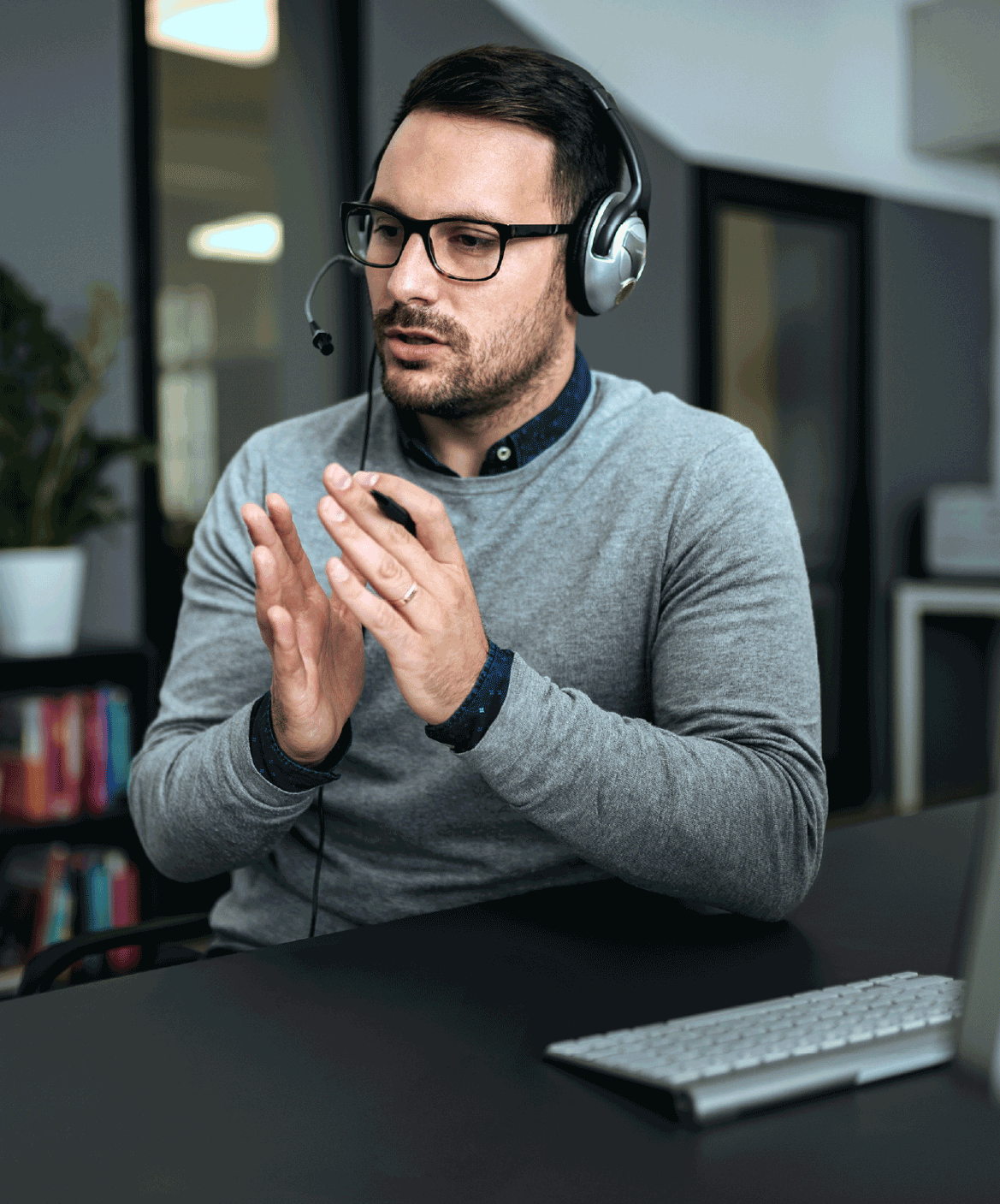 Et billede af en mand, der taler i et headset og forklarer noget med hænderne