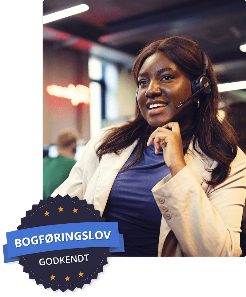 En kvinde sidder med headset på og smiler ud i luften