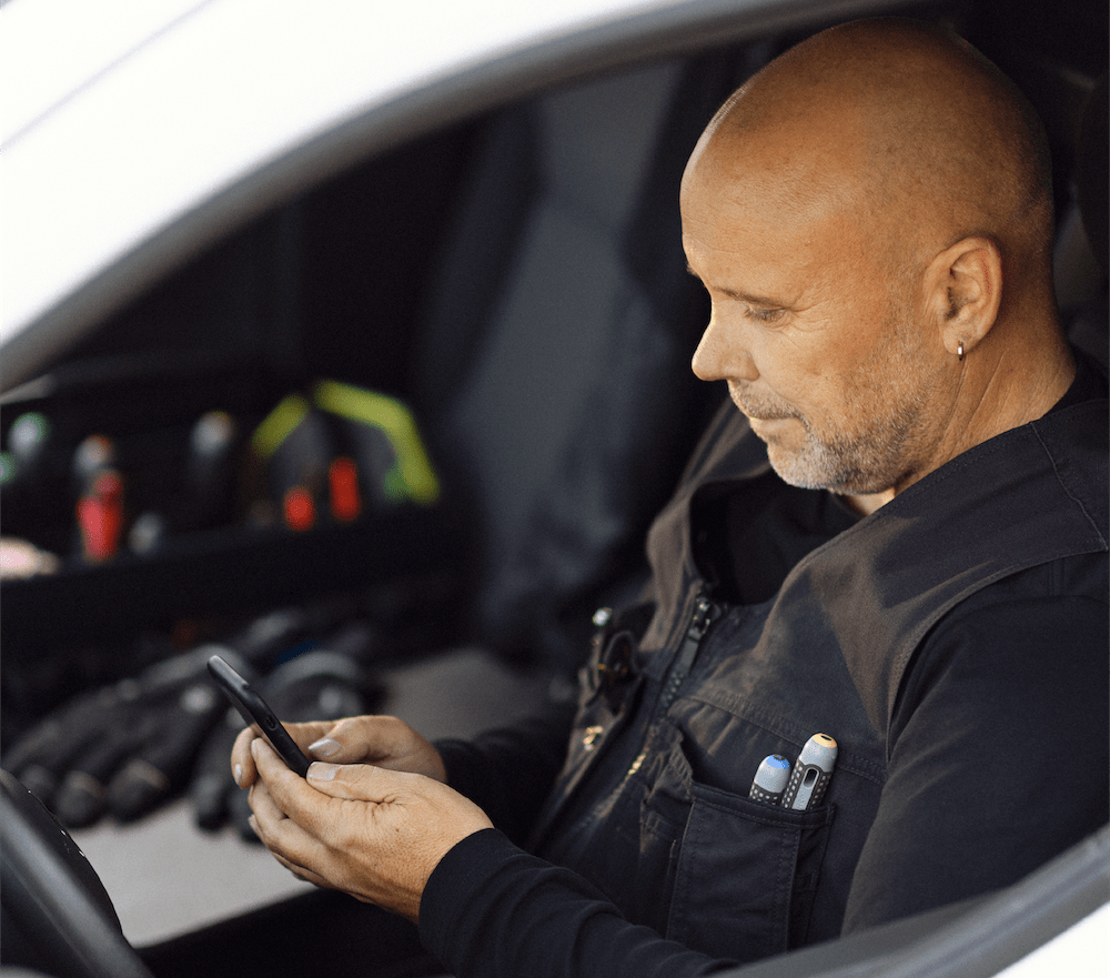 håndværker i bil der indsender bilag via e-conomic mobilapp 