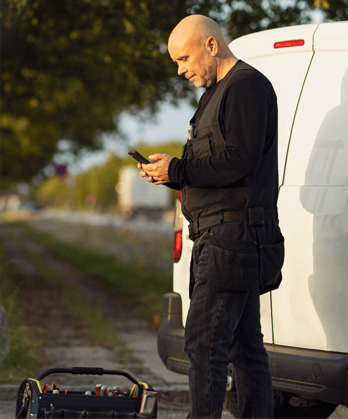 håndværker indsender bilag mens hans arbejder ved sin bil