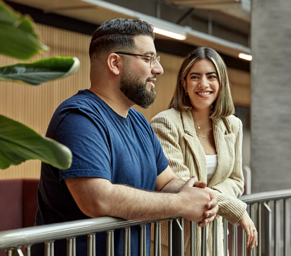 To mennesker står og snakker sammen på en arbejdsplads