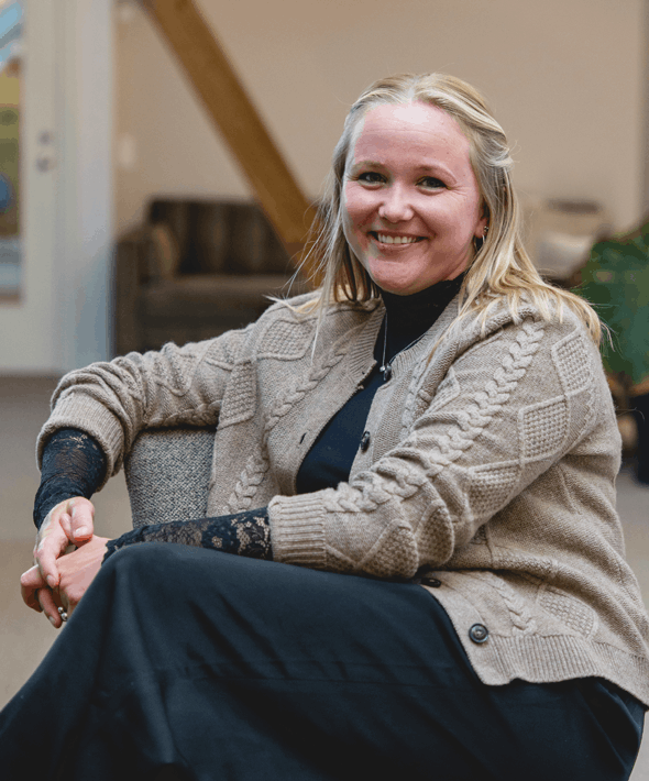 En kvinde sidder i en sofa og smiler til kameraet