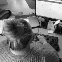 Et billede af en kvinde oppefra, der sidder ved en computer