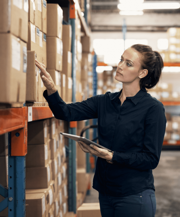 En kvinde står på et lager og kigger på en kasse